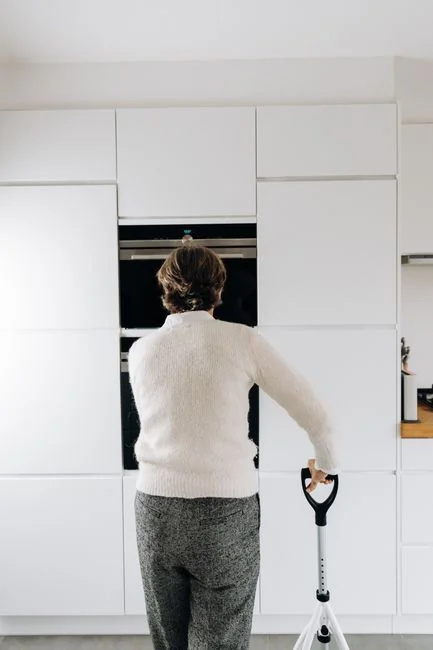 A woman in a protective suit disinfects an indoor space with fogging equipment.